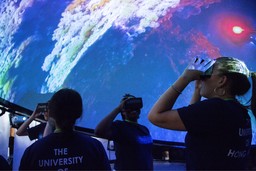 學生置身沉浸式360度全景投影系統imseDOME，利用VR觀景器欣賞影片。
